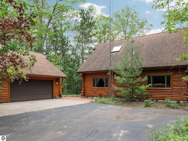 10037 Mud Lake Rd, Interlochen, MI 49643 - view of home's exterior with a shingled roof, log exterior, and a garage
