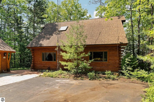 10037 Mud Lake Rd, Interlochen, MI 49643 - cabin with log exterior and roof with shingles