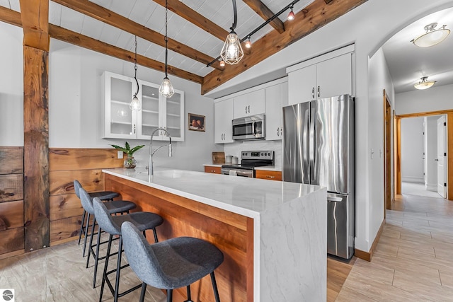 3872 Falling Leaf Trl, Traverse City, MI 49686 - kitchen with stainless steel appliances, a kitchen bar, glass insert cabinets, a peninsula, and pendant lighting