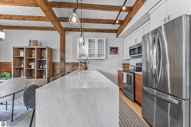 3872 Falling Leaf Trl, Traverse City, MI 49686 - kitchen featuring appliances with stainless steel finishes, glass insert cabinets, a peninsula, white cabinets, and a breakfast bar