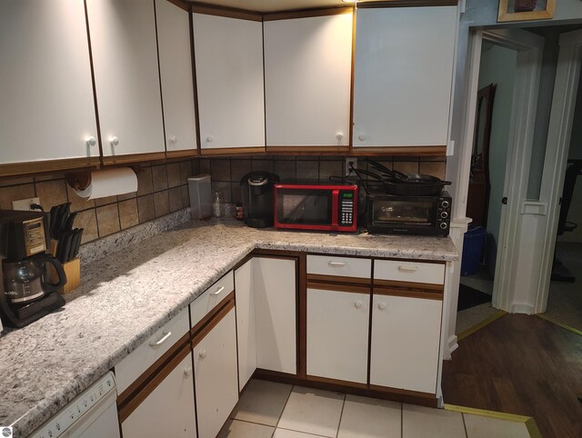 5094 SW Old Butler Rd Unit 1, South Boardman, MI 49680 - kitchen featuring white cabinets, light countertops, backsplash, dishwasher, and light wood finished floors
