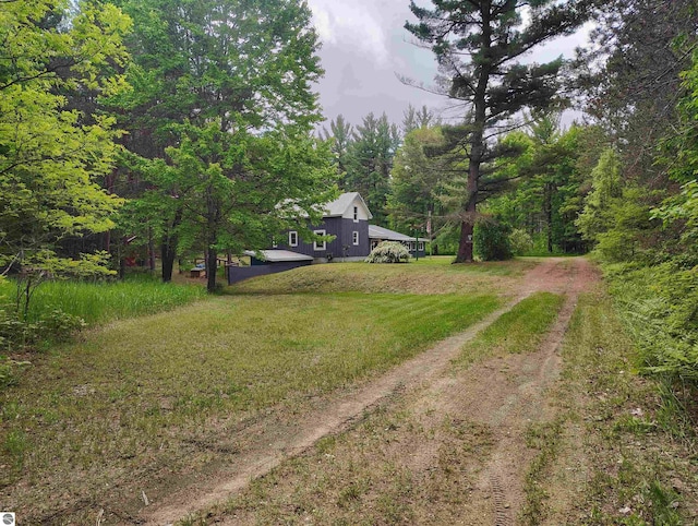 5094 SW Old Butler Rd Unit 1, South Boardman, MI 49680 - view of green lawn featuring dirt driveway and a forest view