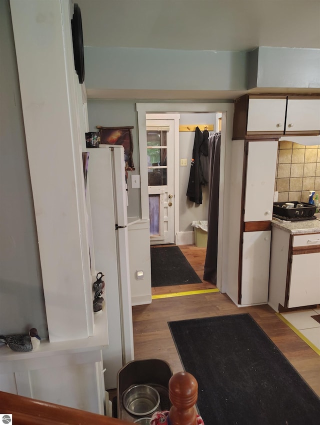 5094 SW Old Butler Rd Unit 1, South Boardman, MI 49680 - kitchen featuring white cabinetry, tasteful backsplash, wood finished floors, and freestanding refrigerator
