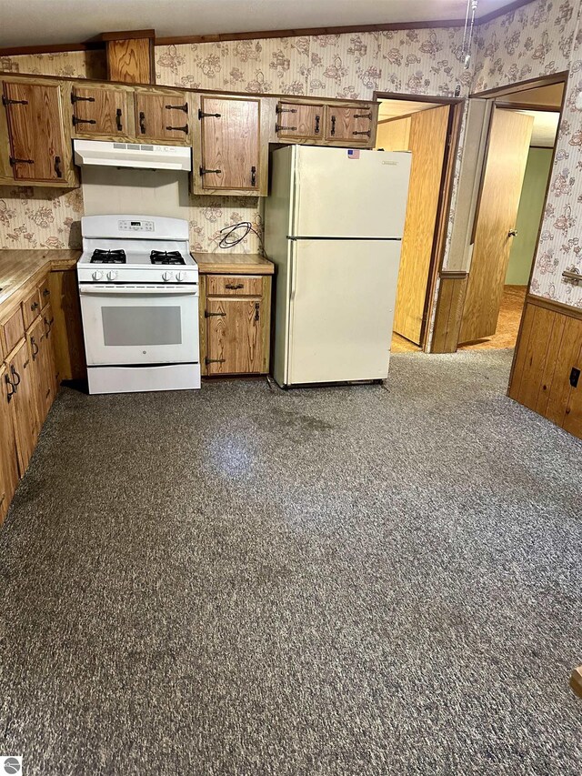 8334 Cinder Hill Rd, Mancelona, MI 49659 - kitchen with white appliances, under cabinet range hood, wallpapered walls, brown cabinets, and wainscoting