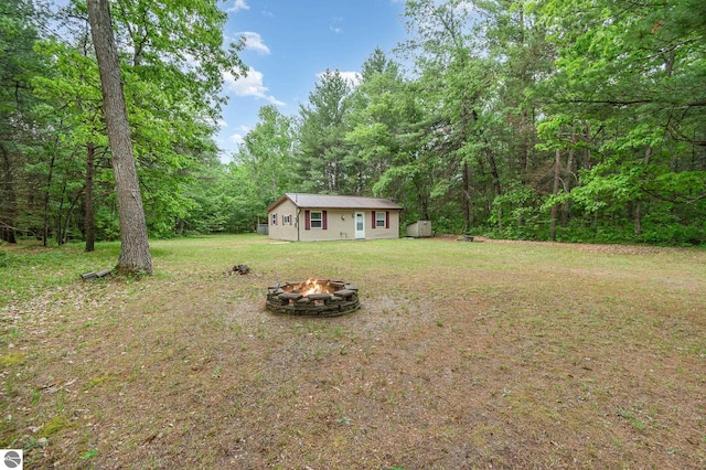 7373 Blue Ox Trl, South Branch, MI 48761 - view of grassy yard with a fire pit and a view of trees