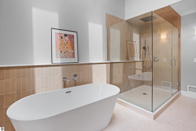 4340 E Huron River Dr, Ann Arbor, MI 48105 - full bath featuring tile walls, a soaking tub, a stall shower, and a wainscoted wall