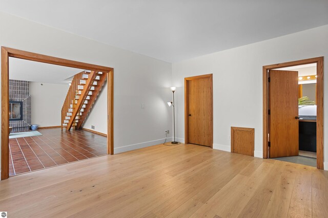 4340 E Huron River Dr, Ann Arbor, MI 48105 - unfurnished living room with stairway, wood finished floors, and a tiled fireplace