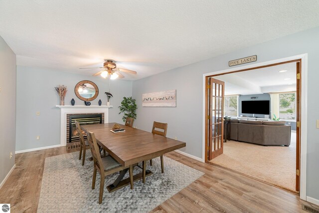 7746 Five Lakes Dr, Farwell, MI 48622 - dining area with a ceiling fan, wood finished floors, and a brick fireplace