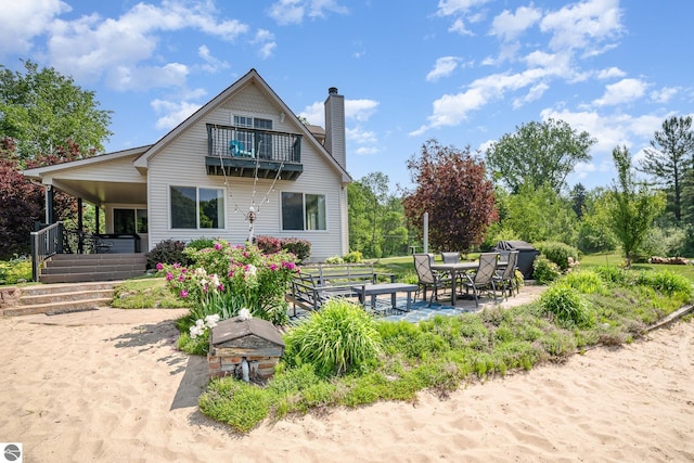 7746 Five Lakes Dr, Farwell, MI 48622 - rear view of property with a chimney, a balcony, a patio, and outdoor dining area