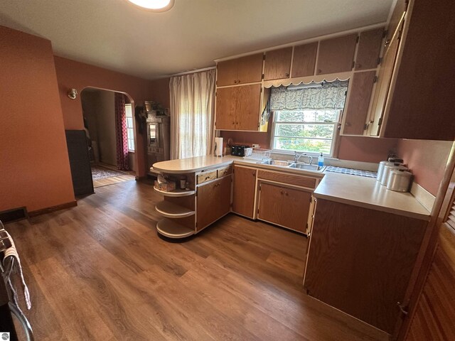 501 W 13th St, Cadillac, MI 49601 - kitchen featuring arched walkways, wood finished floors, light countertops, and a peninsula