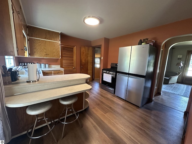 501 W 13th St, Cadillac, MI 49601 - kitchen featuring appliances with stainless steel finishes, light countertops, a peninsula, dark wood finished floors, and arched walkways
