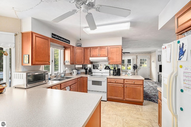 2902 N Dr, Traverse City, MI 49685 - kitchen featuring white appliances, a ceiling fan, under cabinet range hood, and a peninsula