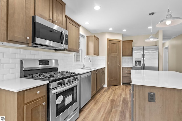 3874 Falling Leaf Trl, Traverse City, MI 49686 - kitchen featuring stainless steel appliances, light wood-style floors, hanging light fixtures, decorative backsplash, and light countertops