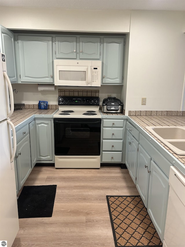 4673 N Crossover Dr, Bellaire, MI 49615 - kitchen featuring white appliances, light wood-style floors, and tile countertops