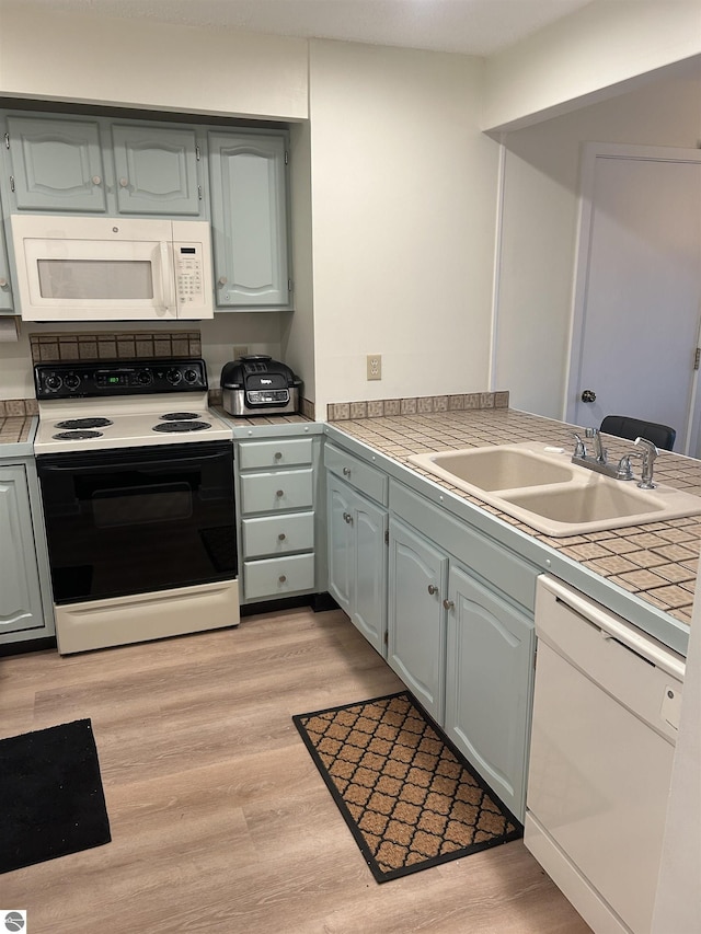 4673 N Crossover Dr, Bellaire, MI 49615 - kitchen featuring white appliances, light wood-type flooring, tile counters, and a peninsula