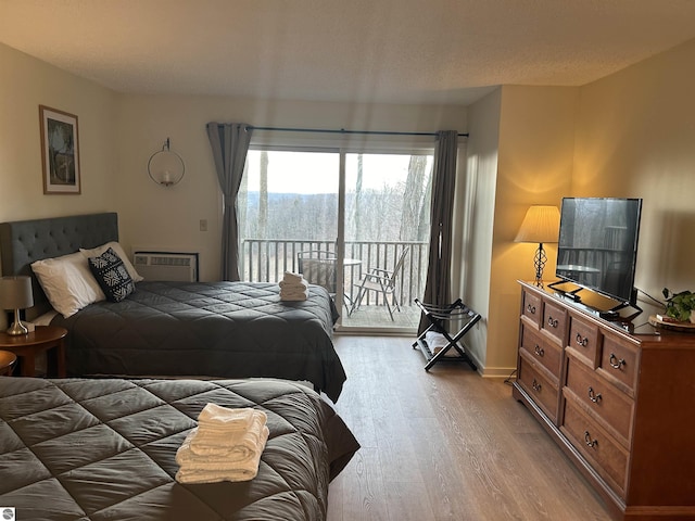 4673 N Crossover Dr, Bellaire, MI 49615 - bedroom featuring access to exterior, light wood-type flooring, and a wall mounted air conditioner