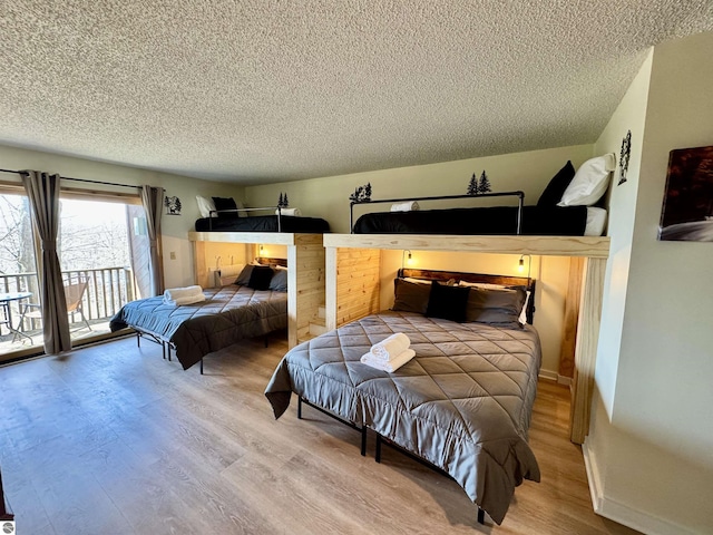 4673 N Crossover Dr, Bellaire, MI 49615 - bedroom featuring a textured ceiling, access to outside, and wood finished floors