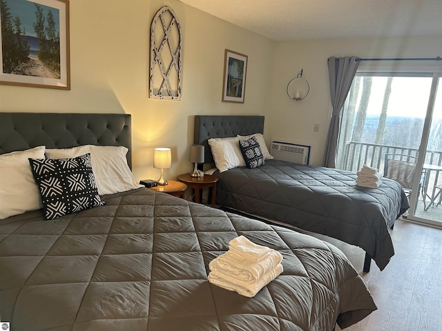 4673 N Crossover Dr, Bellaire, MI 49615 - bedroom featuring access to outside, multiple windows, a wall mounted air conditioner, and wood finished floors