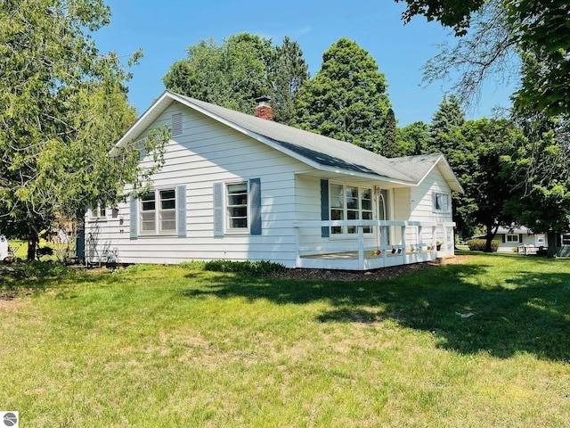 801 N Bridge St, Bellaire, MI 49615 - view of home's exterior with a chimney and a lawn