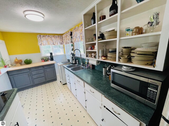 801 N Bridge St, Bellaire, MI 49615 - kitchen featuring stainless steel microwave, a textured ceiling, light floors, white cabinetry, and open shelves