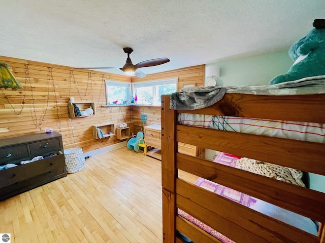 801 N Bridge St, Bellaire, MI 49615 - bedroom featuring a textured ceiling, wooden walls, hardwood / wood-style flooring, and ceiling fan