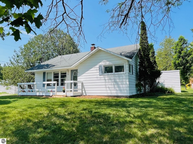 801 N Bridge St, Bellaire, MI 49615 - back of property with a yard, a chimney, a wooden deck, and roof with shingles