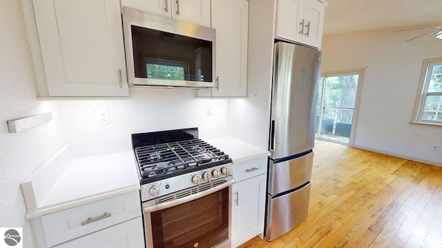 7500 Five Lakes Dr, Farwell, MI 48622 - kitchen with stainless steel appliances, light wood-style floors, light countertops, and white cabinetry