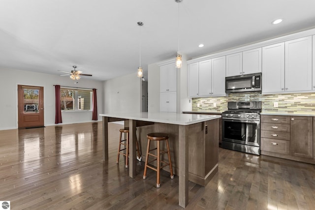 301 Pearl St, Kingsley, MI 49649 - kitchen with appliances with stainless steel finishes, decorative backsplash, a kitchen island, dark wood-type flooring, and light countertops