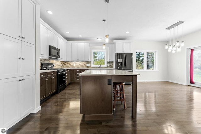 301 Pearl St, Kingsley, MI 49649 - kitchen with black appliances, dark wood-style floors, a kitchen island, backsplash, and recessed lighting