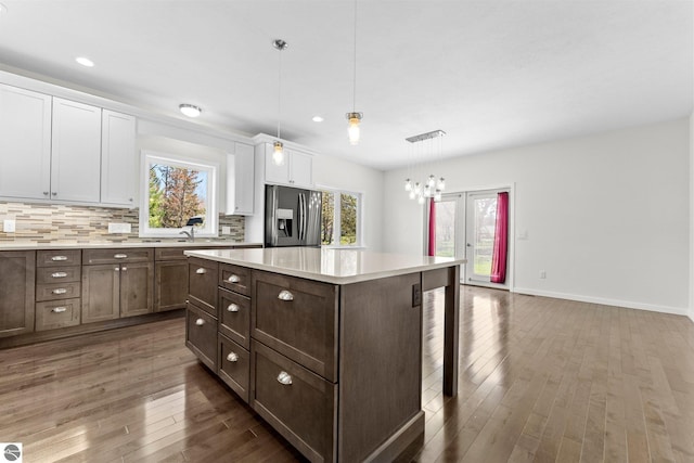 301 Pearl St, Kingsley, MI 49649 - kitchen with stainless steel fridge with ice dispenser, white cabinetry, a breakfast bar, light countertops, and wood finished floors