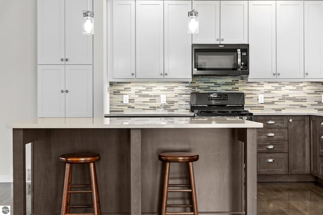 301 Pearl St, Kingsley, MI 49649 - kitchen featuring black microwave, stove, a kitchen breakfast bar, decorative backsplash, and light countertops