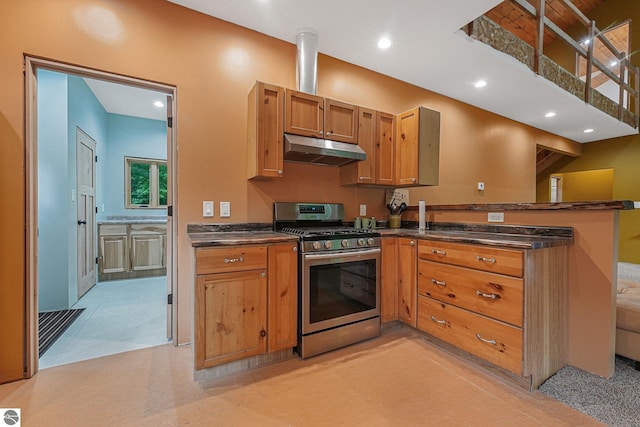 1849 W 24th Rd, Boon, MI 49618 - kitchen with gas stove, under cabinet range hood, dark countertops, a peninsula, and brown cabinetry