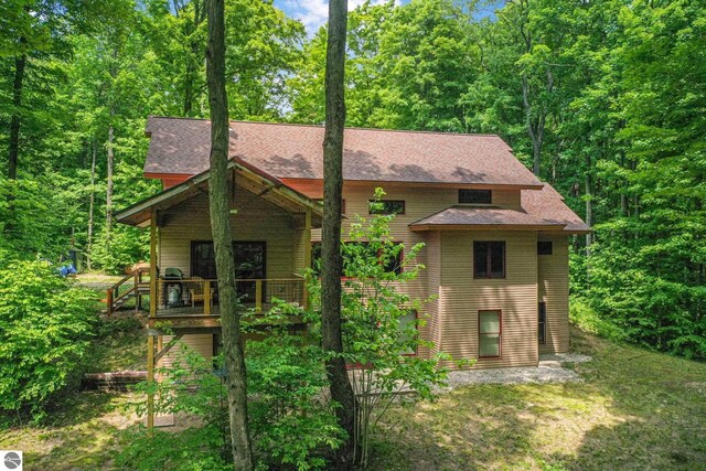 1849 W 24th Rd, Boon, MI 49618 - rustic home featuring a shingled roof and a wooded view