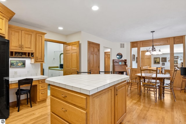 6352 S Westwood Pkwy, Suttons Bay, MI 49682 - kitchen with tile countertops, light wood-style floors, a kitchen island, recessed lighting, and pendant lighting