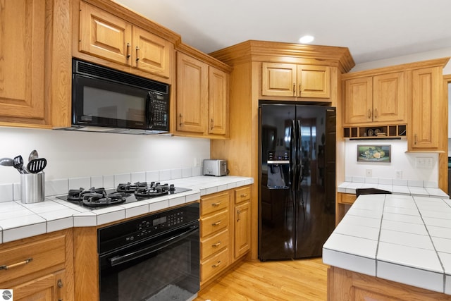 6352 S Westwood Pkwy, Suttons Bay, MI 49682 - kitchen with black appliances, tile countertops, light wood-style flooring, and recessed lighting