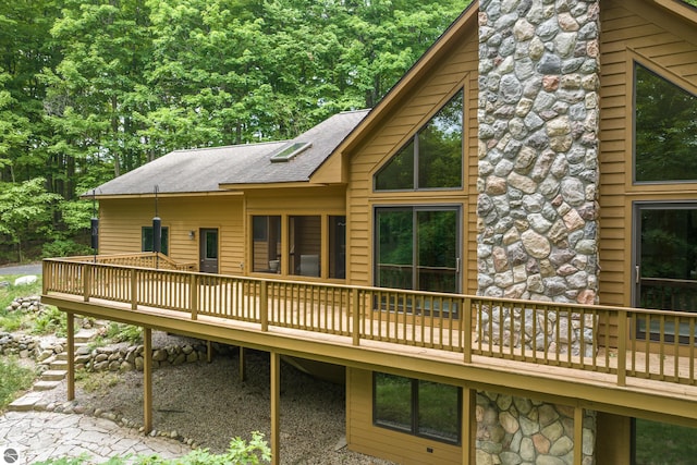 6352 S Westwood Pkwy, Suttons Bay, MI 49682 - back of house with a wooden deck, a shingled roof, and stone siding