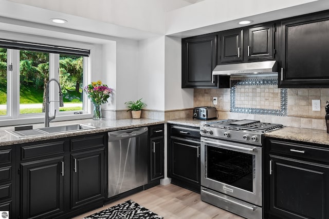 1259 Lin Dale Dr, Traverse City, MI 49686 - kitchen featuring appliances with stainless steel finishes, dark cabinetry, under cabinet range hood, backsplash, and recessed lighting