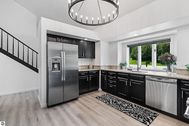 1259 Lin Dale Dr, Traverse City, MI 49686 - kitchen featuring appliances with stainless steel finishes, dark cabinetry, light stone countertops, and light wood-style flooring