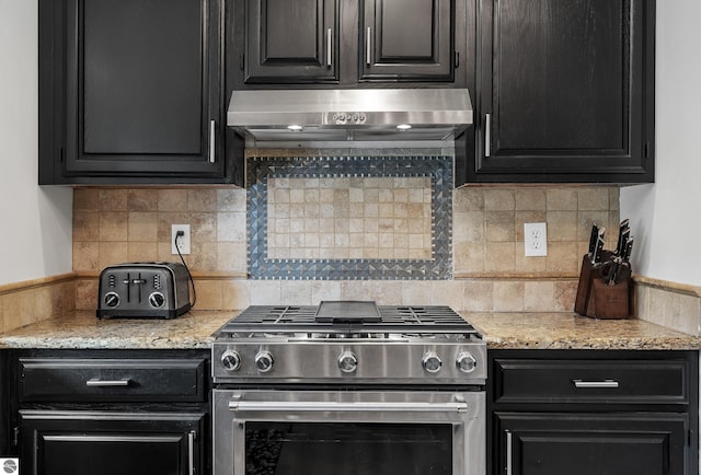 1259 Lin Dale Dr, Traverse City, MI 49686 - kitchen featuring stainless steel range with gas stovetop, under cabinet range hood, dark cabinets, and decorative backsplash
