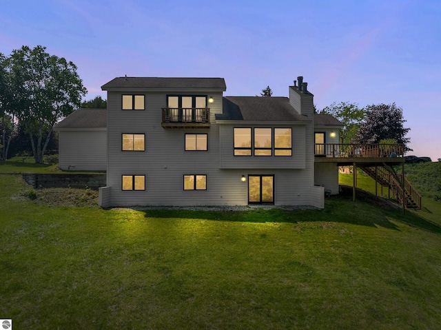 1259 Lin Dale Dr, Traverse City, MI 49686 - back of property at dusk with stairway, a balcony, a chimney, a lawn, and a wooden deck