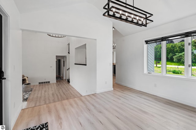 1259 Lin Dale Dr, Traverse City, MI 49686 - unfurnished living room featuring a chandelier, wood finished floors, and high vaulted ceiling