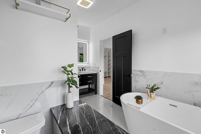 1259 Lin Dale Dr, Traverse City, MI 49686 - full bathroom with tile walls, marble tiled floors, a soaking tub, vanity, and a wainscoted wall
