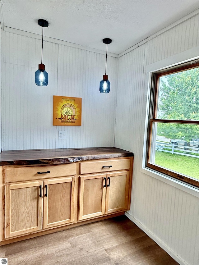 7160 Cherry Ave, Kewadin, MI 49648 - interior space with light wood-style floors, hanging light fixtures, and a textured ceiling
