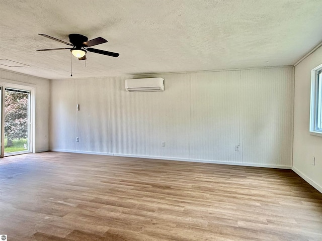 7160 Cherry Ave, Kewadin, MI 49648 - spare room featuring a wall unit AC, wood finished floors, a textured ceiling, plenty of natural light, and ceiling fan
