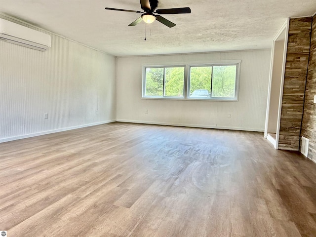 7160 Cherry Ave, Kewadin, MI 49648 - spare room featuring a wall mounted air conditioner, a ceiling fan, and wood finished floors