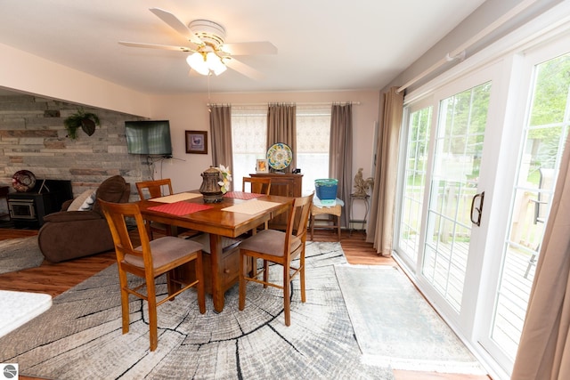 10200 S Lake Station Ave, Lake, MI 48632 - dining room with light wood finished floors, a ceiling fan, a wood stove, and wooden walls