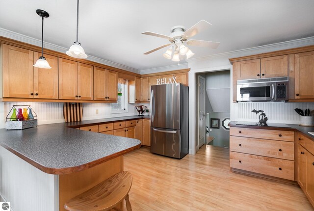 589 Pine Ln, East Tawas, MI 48730 - kitchen featuring stainless steel appliances, dark countertops, a peninsula, pendant lighting, and ceiling fan
