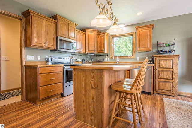 6375 S Isabella Rd, Shepherd, MI 48883 - kitchen with stainless steel appliances, wood finished floors, a center island, light countertops, and recessed lighting