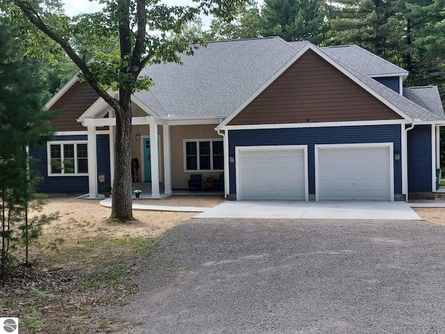 1379 Kunze Rd, East Tawas, MI 48730 - view of front facade featuring an attached garage, concrete driveway, roof with shingles, and covered porch