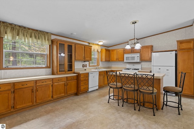 11748 NE Franklin St, Kalkaska, MI 49646 - kitchen with white appliances, brown cabinetry, vaulted ceiling, light countertops, and plenty of natural light
